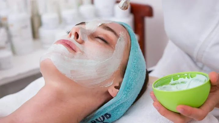 woman lying on blue towel with white cream on face